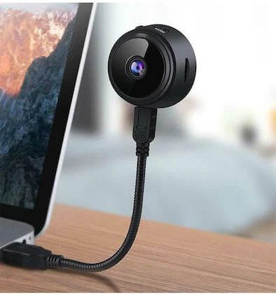 Mini wireless security camera connected to laptop, ideal for indoor and outdoor monitoring with HD resolution and night vision.